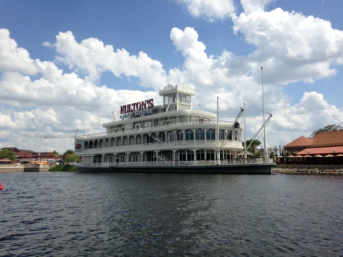White riverboat-shaped restaurant building with a Fulton's Crab House sign, seen across the water.