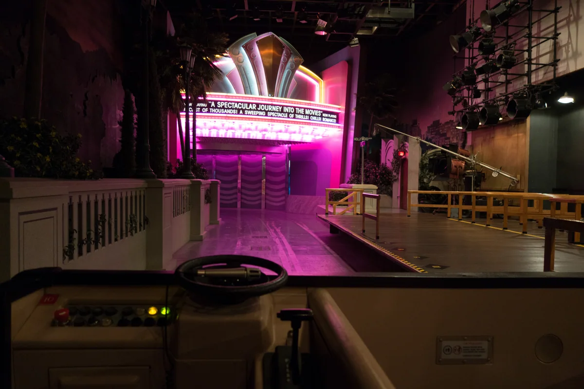View over a ride vehicle's steering wheel toward the Great Movie Ride's illuminated loading-area marquee.