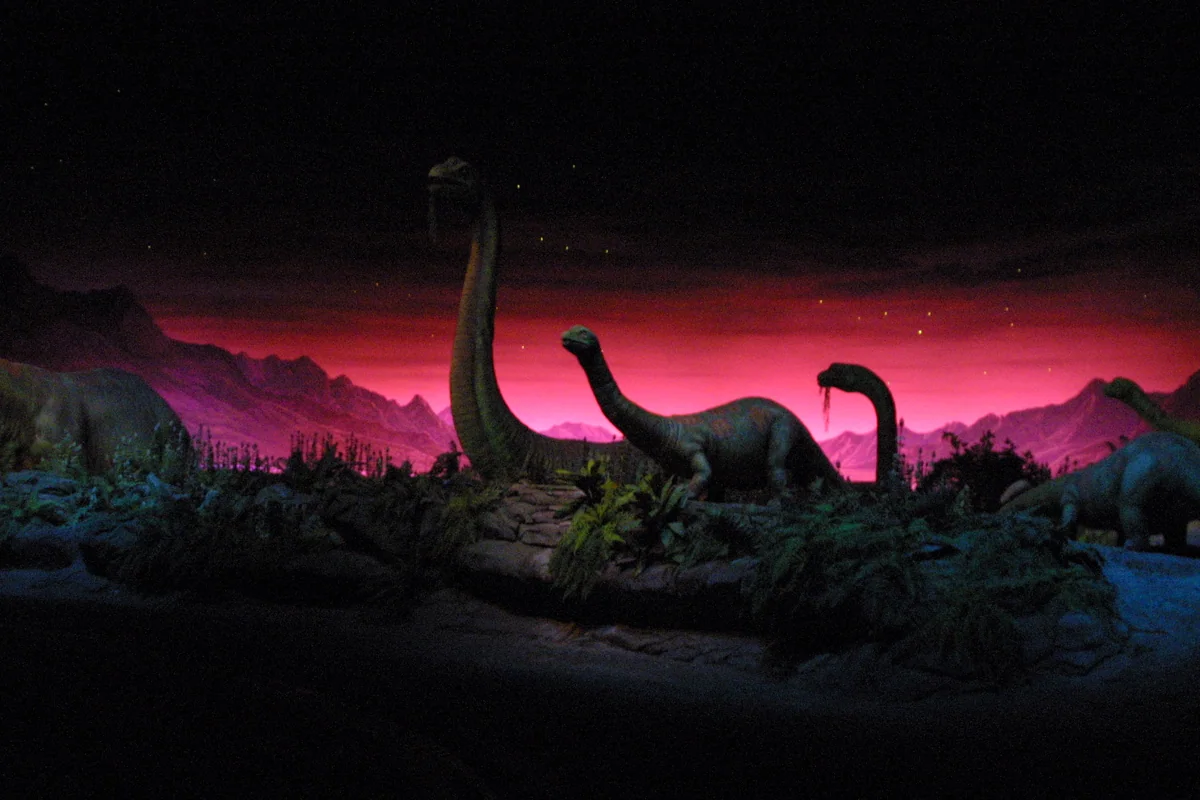 Long-necked dinosaur figures against a red and purple prehistoric landscape inside Universe of Energy.