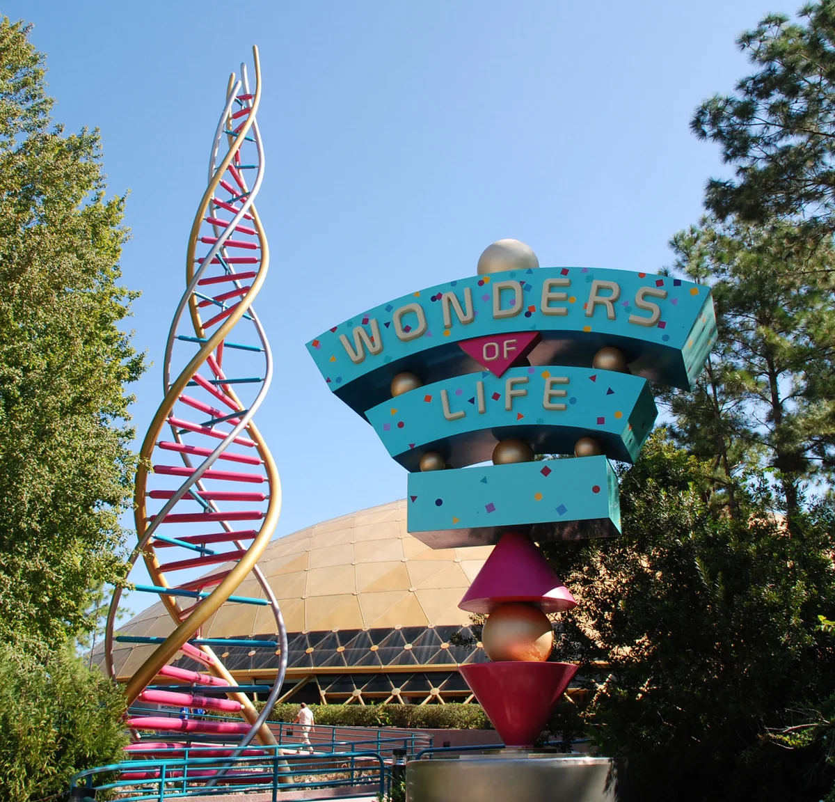 Colorful Wonders of Life entrance sign beside a double-helix sculpture, with the gold pavilion dome behind.